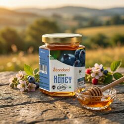 Natural berry honey in glass jar with wooden dipper, placed outdoors with fresh berries and flowers, pure organic honey product