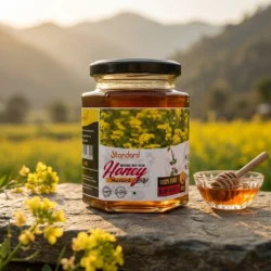 100 percent pure mustard honey in glass jar with honey dipper and mustard flowers, natural organic honey product