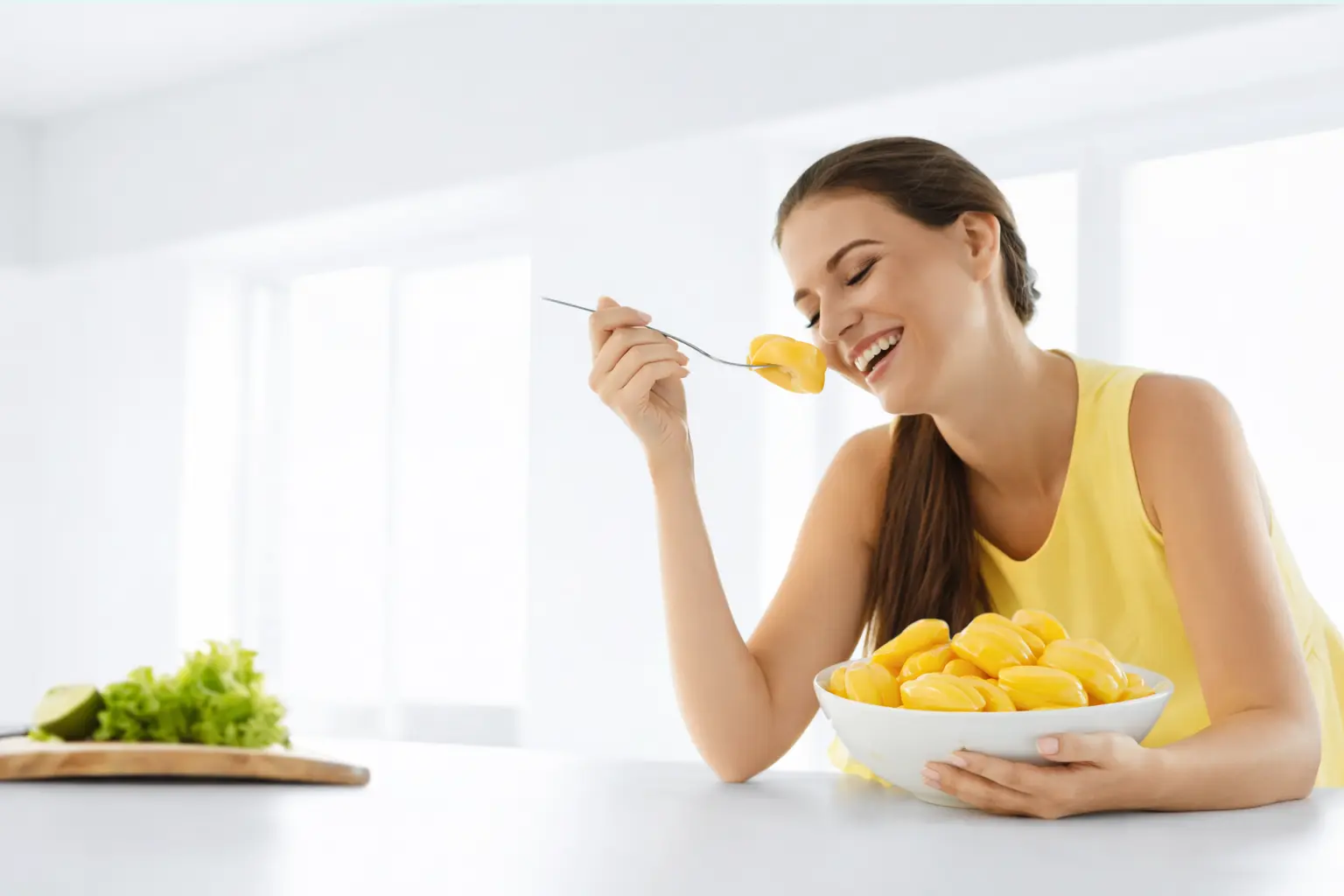 Smiling Woman Enjoying Fresh Ripe Jackfruit From A Bowl In A Bright, Healthy Kitchen Setting